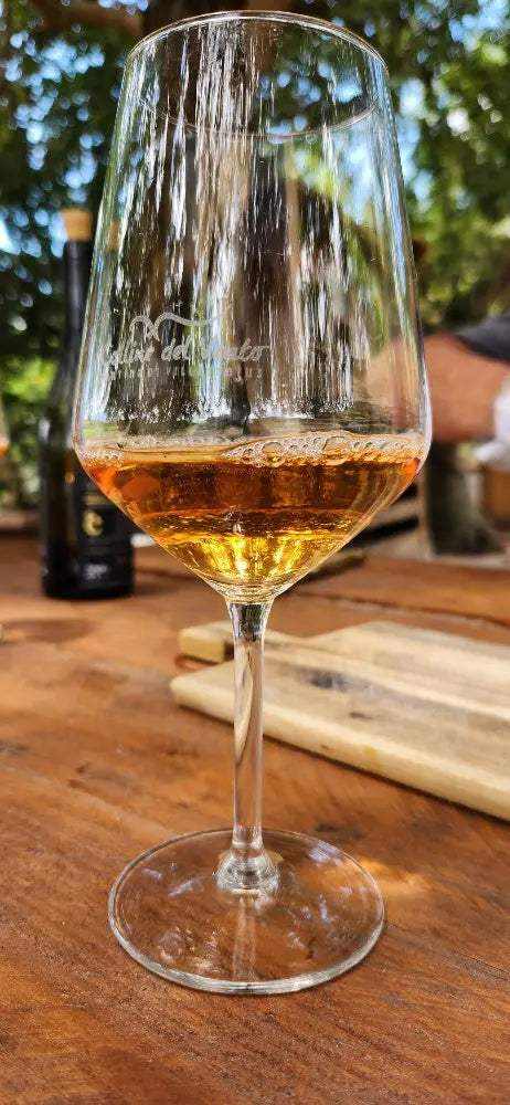 Bottiglie di orange wine dal colore ambrato con calici di vino su sfondo rustico