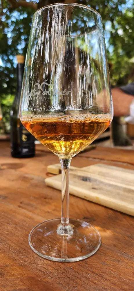 Bottiglie di orange wine dal colore ambrato con calici di vino su sfondo rustico