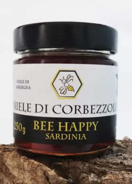 Barattolo di miele di corbezzolo ambrato scuro tipico della Sardegna con fiori e bacche di corbezzolo sullo sfondo