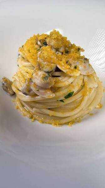 Spaghetti con vongole veraci e bottarga di muggine, piatto tipico sardo condito con prezzemolo e olio extravergine d'oliva.
