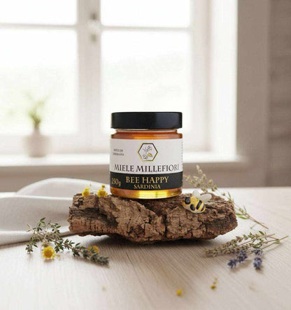 Miele di Millefiori in vasetto di vetro con tappo nero, etichetta bianca e dorata e miele ambrato